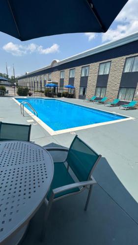 a pool with a table and chairs and an umbrella at Rodeway Inn in Barboursville