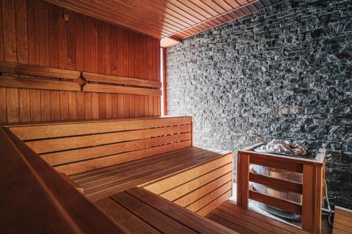 a sauna with a wooden bench and a stone wall at Apartmán KaTry in Veľká Lomnica