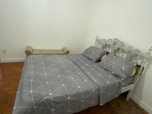 a bed with a gray comforter and two pillows at Apartamento Historico Beira Mar - Na avenida da Praia in Santos