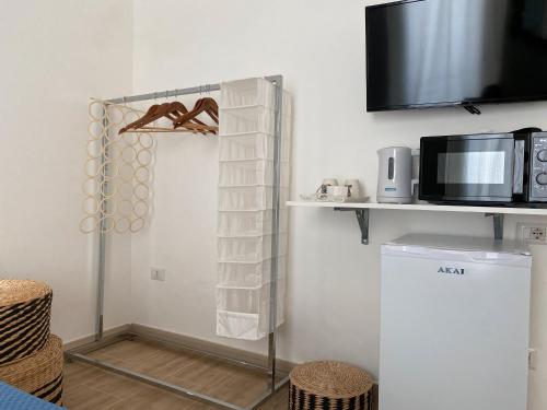 a kitchen with a shelf with towels and a microwave at Isid'Oro Rooms - 100m from the sea in Sant'Isidoro