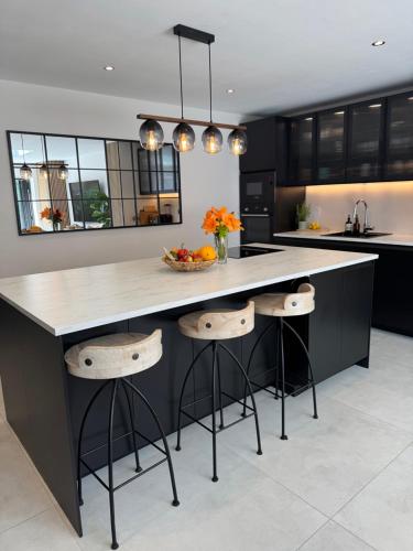 a kitchen with a large island with stools in it at Modern Luxury Home with Spacious Garden close to Warner Bros Studio in Abbots Langley