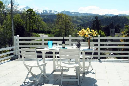 une table et des chaises blanches sur une terrasse avec des montagnes dans l'établissement Chez RAYMOND, à Ordizan