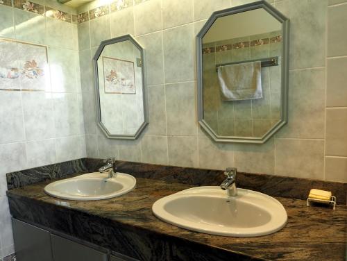 une salle de bain avec deux lavabos et deux miroirs dans l'établissement Chez RAYMOND, à Ordizan