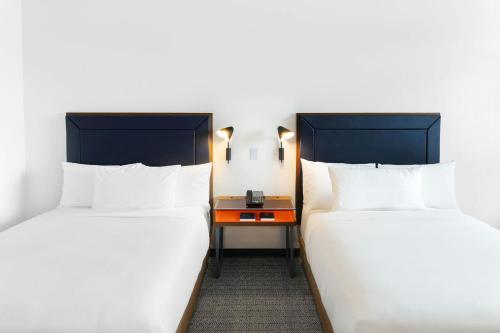 two beds in a room with a table between them at Courtyard by Marriott Mexico City Airport in Mexico City