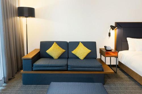 a blue couch with yellow pillows in a hotel room at Courtyard by Marriott Mexico City Airport in Mexico City