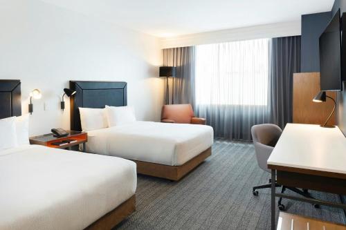 a hotel room with two beds and a desk at Courtyard by Marriott Mexico City Airport in Mexico City