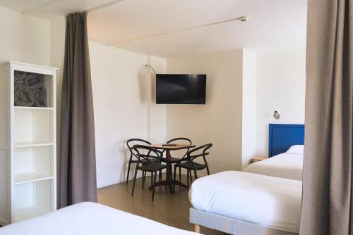 a room with two beds and a table with chairs at Hôtel Les Rives Bleues in La Grande-Motte