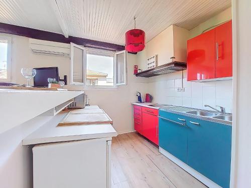 une cuisine avec des armoires rouges et bleues et une fenêtre dans l'établissement Apartment Le Mascoïnat by Interhome, à Nice