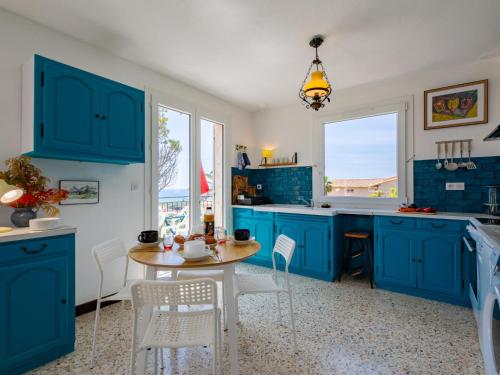 une cuisine avec des armoires bleues et une table et des chaises dans l'établissement Apartment Boudi-ou by Interhome, à Anthéor