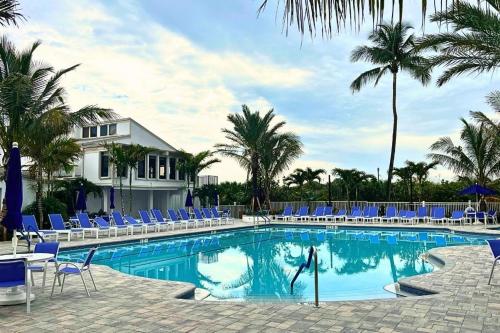 a swimming pool with blue chairs and palm trees at Dreamy Condo 2 minute walk to Beach w King Size Bd in Fort Pierce