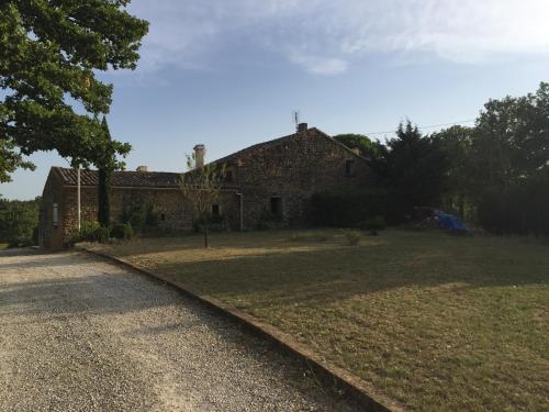 une vieille maison en pierre avec une cour gazonnée à côté d'une route dans l'établissement Maison de caractère, à Saint-Montan