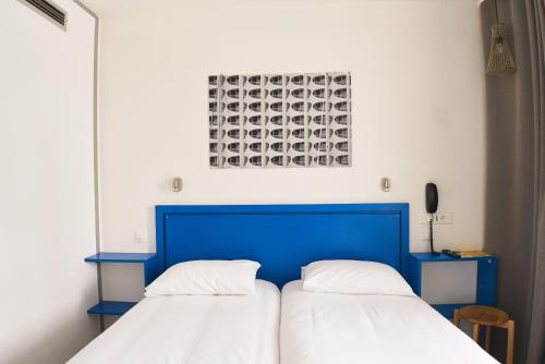 two beds in a room with a blue headboard at Hôtel Les Rives Bleues in La Grande-Motte