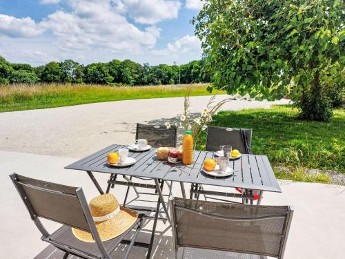 a picnic table with two chairs and oranges on it at Holiday Home La Trélennoise by Interhome in Plonéour-Lanvern