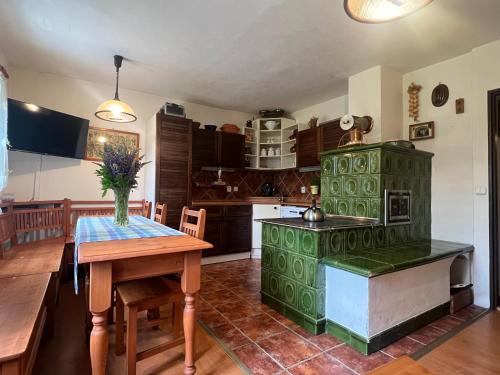 a kitchen with a table and a green stove at Chalupa Peťka in Rudník