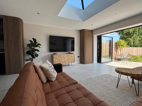 a living room with a brown couch and a television at Modern Luxury Home with Spacious Garden close to Warner Bros Studio in Abbots Langley