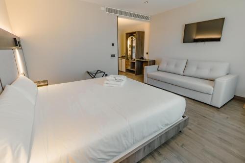 a bedroom with a large white bed and a couch at HOTEL RURAL FINCA LA DESA in Miajadas
