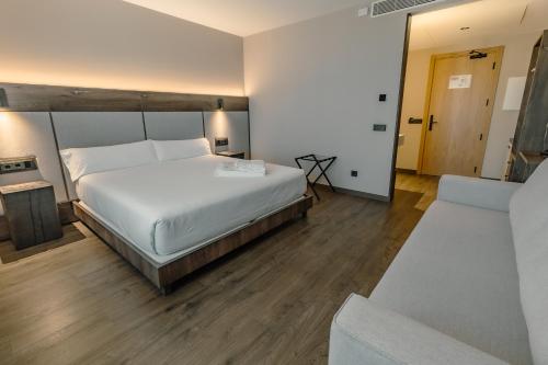 a bedroom with a large white bed and a couch at HOTEL RURAL FINCA LA DESA in Miajadas