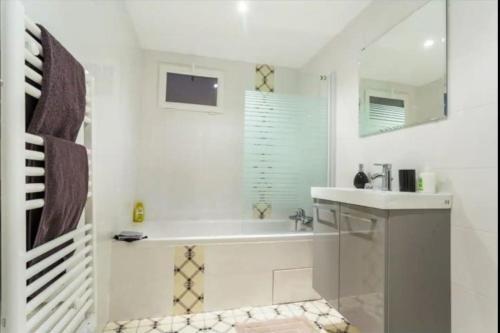 La salle de bains blanche est pourvue d'un lavabo et d'une baignoire. dans l'établissement 3 pièces Arc de Triomphe RDC, à Paris