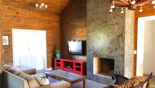 un soggiorno con camino e televisione di Casa Oliva com piscina e 6 quartos a Rancho Queimado