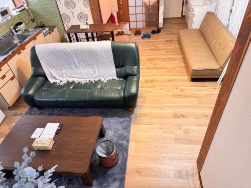 a living room with a green leather couch and a table at お宿花水木 in Nagasaki