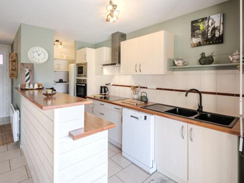 une cuisine avec des armoires blanches et un évier dans l'établissement Holiday Home La Chapelle by Interhome, à Contis-les-Bains