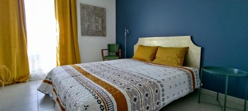 une chambre avec un lit avec un mur bleu dans l'établissement Pause Ciotadenne, à La Ciotat