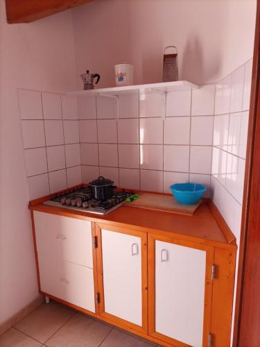 a small kitchen with a stove and white tiles at Penthouse a stone's throw from the sea in Santa Maria