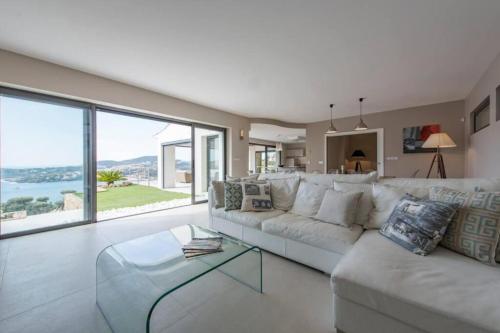 a living room with a white couch and large windows at Spacious house with pool - near beach in Saint-Raphaël