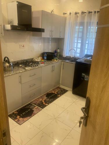 una cucina con mobili bianchi e un frigorifero nero di ADES Home a Lekki