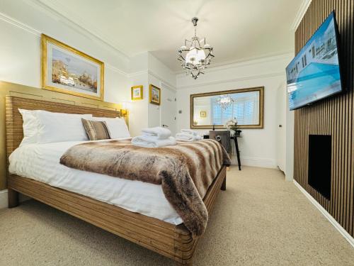 a bedroom with a large bed and a chandelier at Luxury Designer 2-Bedroom Apartment with Private Garden & Free Parking in Bexleyheath