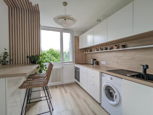 une cuisine avec lave-linge et sèche-linge ainsi qu'une fenêtre dans l'établissement T2 au calme, balcon, proche métro, parking gratuit, à Caluire-et-Cuire
