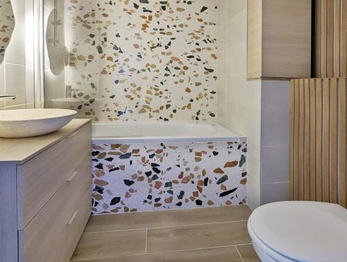 une salle de bain avec toilettes, lavabo et baignoire dans l'établissement T2 au calme, balcon, proche métro, parking gratuit, à Caluire-et-Cuire