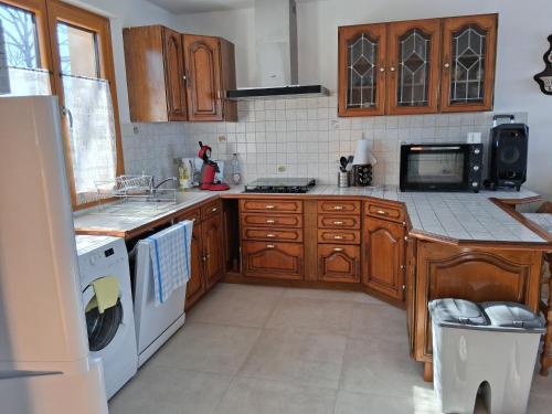 a kitchen with wooden cabinets and a white appliance at Maison Les Sables Un havre de paix au cœur de la in Bouzemont
