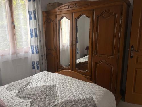 a bedroom with a wooden dresser with a bed and a mirror at Maison Les Sables Un havre de paix au cœur de la in Bouzemont