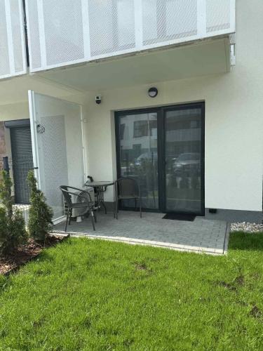 a patio with a table and chairs in front of a house at Apartament Burgund 2 pokojowy z ogródkiem lub pokoje ze wspólną kuchnią i łazienką in Warsaw