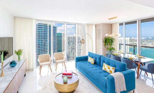 Una sala de estar con un sofá azul y vistas a la ciudad. en MVR - Wake to Water & Skyline Views, en Miami