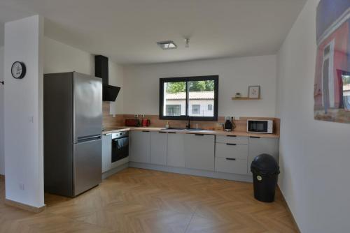 Il comprend une cuisine équipée d'un réfrigérateur en acier inoxydable et une fenêtre. dans l'établissement Villa Evan Climatisation individuelle par pièce proche du centre-ville, à Ruoms