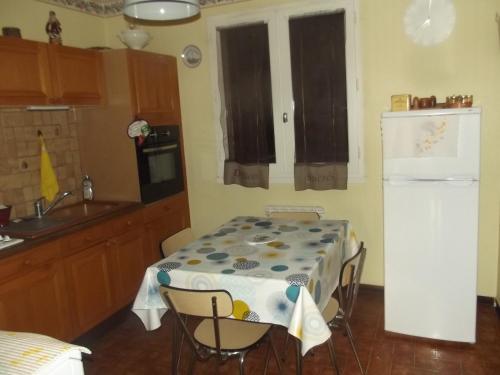 une cuisine avec une table et un réfrigérateur blanc dans l'établissement Cascades Location, à Creissels