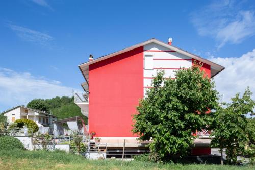 a red and white building with a tree in front of it at Bed & Breakfast Cozy Hills in Cagli
