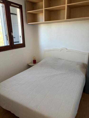 - un lit blanc dans une chambre avec fenêtre dans l'établissement Cocon en bord de mer avec piscine, à Saint Cyprien Plage