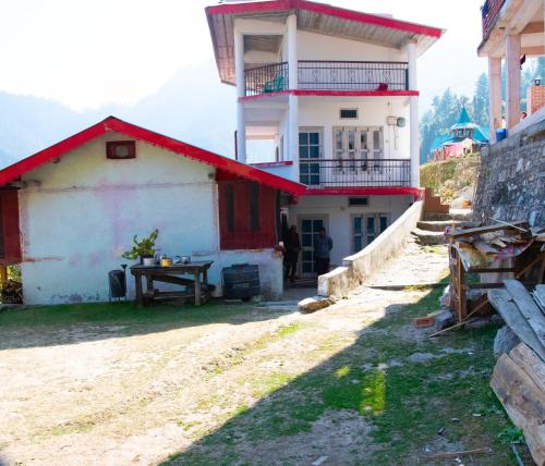 a house with a red roof and a table in front of it at Syanaik Adiyan House in Deoban