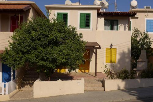 a white house with a tree in front of it at Mediterraneo 27 - Protaras in Protaras