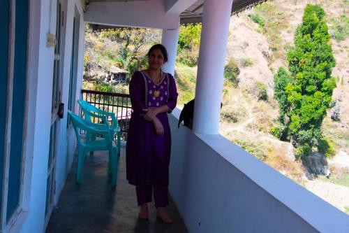 a woman standing on the porch of a house at Syanaik Adiyan House in Deoban