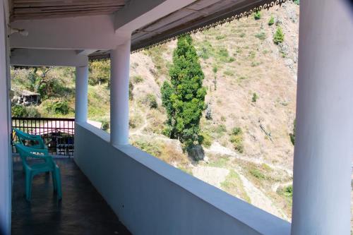 a green chair sitting on a balcony with a view at Syanaik Adiyan House in Deoban