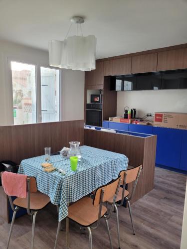 een keuken met een tafel met stoelen en een blauwe bar bij Oacys in Le Barcarès