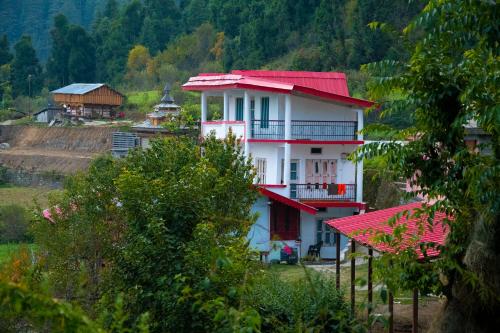 a white house with a red roof on a hill at Syanaik Adiyan House in Deoban