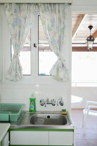 a kitchen with a sink and a window with curtains at Mediterraneo 27 - Protaras in Protaras
