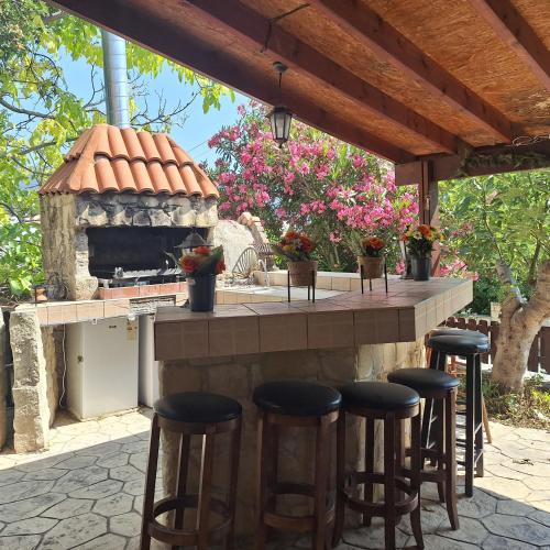 a outdoor kitchen with stools at a bar with a fireplace at Koukaki in Kouka