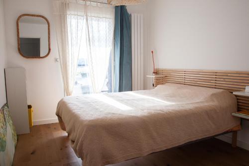une chambre avec un lit, un miroir et une fenêtre dans l'établissement Appartement neuf à 200 m de la plage tout confort, à Pornichet