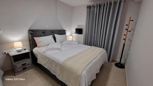 a bedroom with a large white bed and a night stand at Antreas cosy apartment in Paralion astros